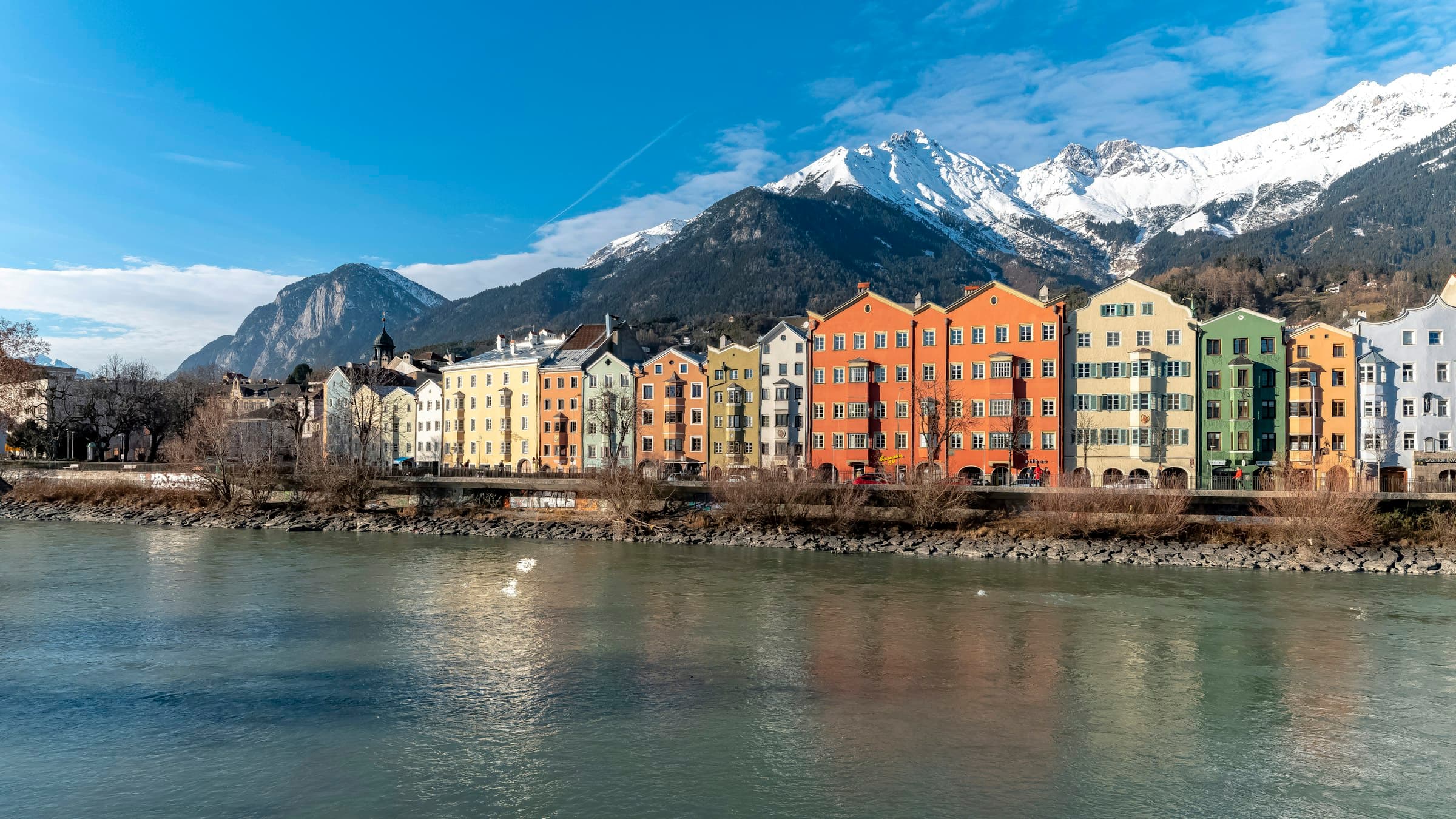 The colourful riverfront houses of Innsbruck's old town beneath the snow-capped peaks of the Nordkette.