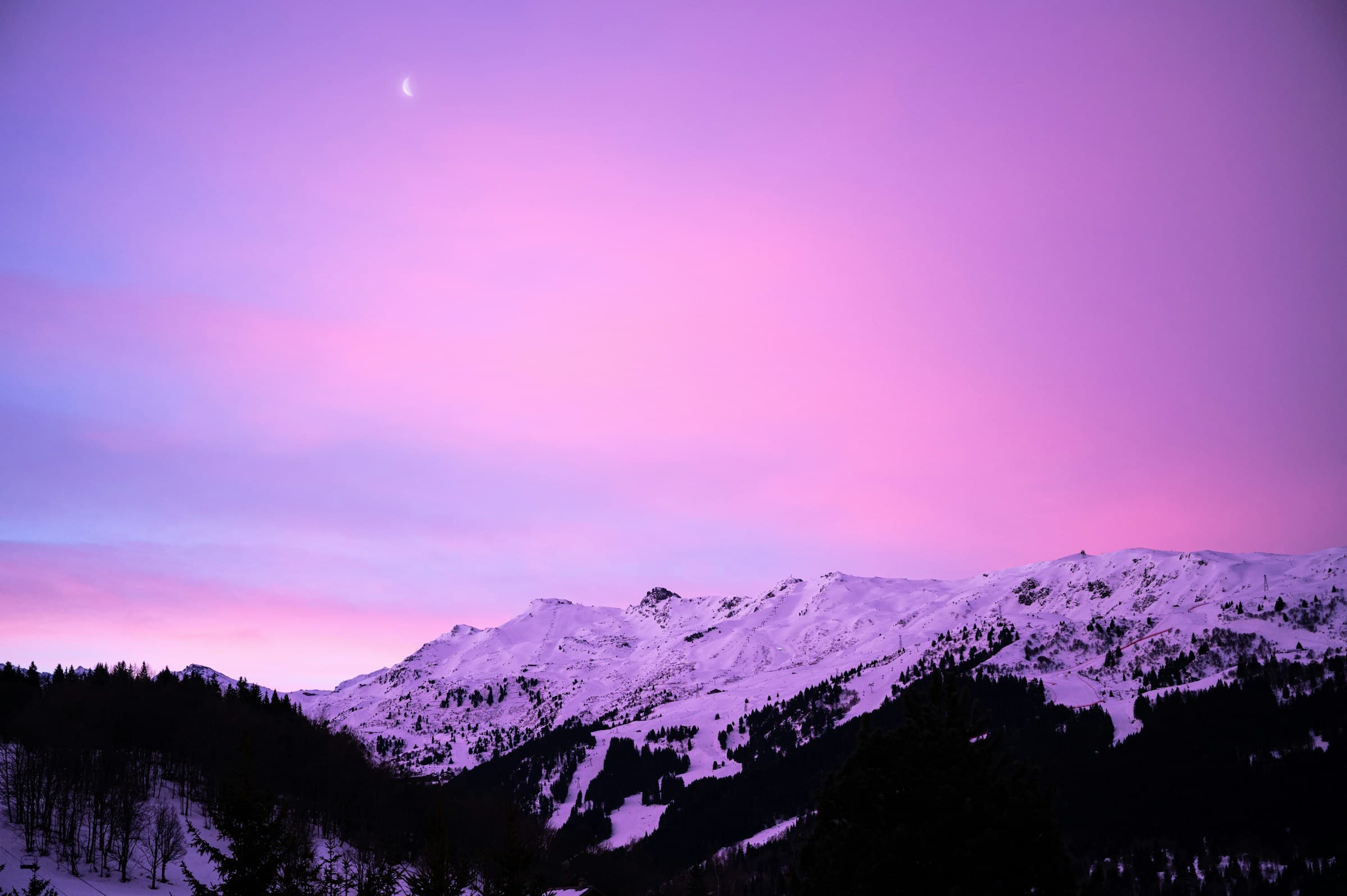 The ridge above Méribel under a deep pink-purple dusk sky, a crescent moon high above.