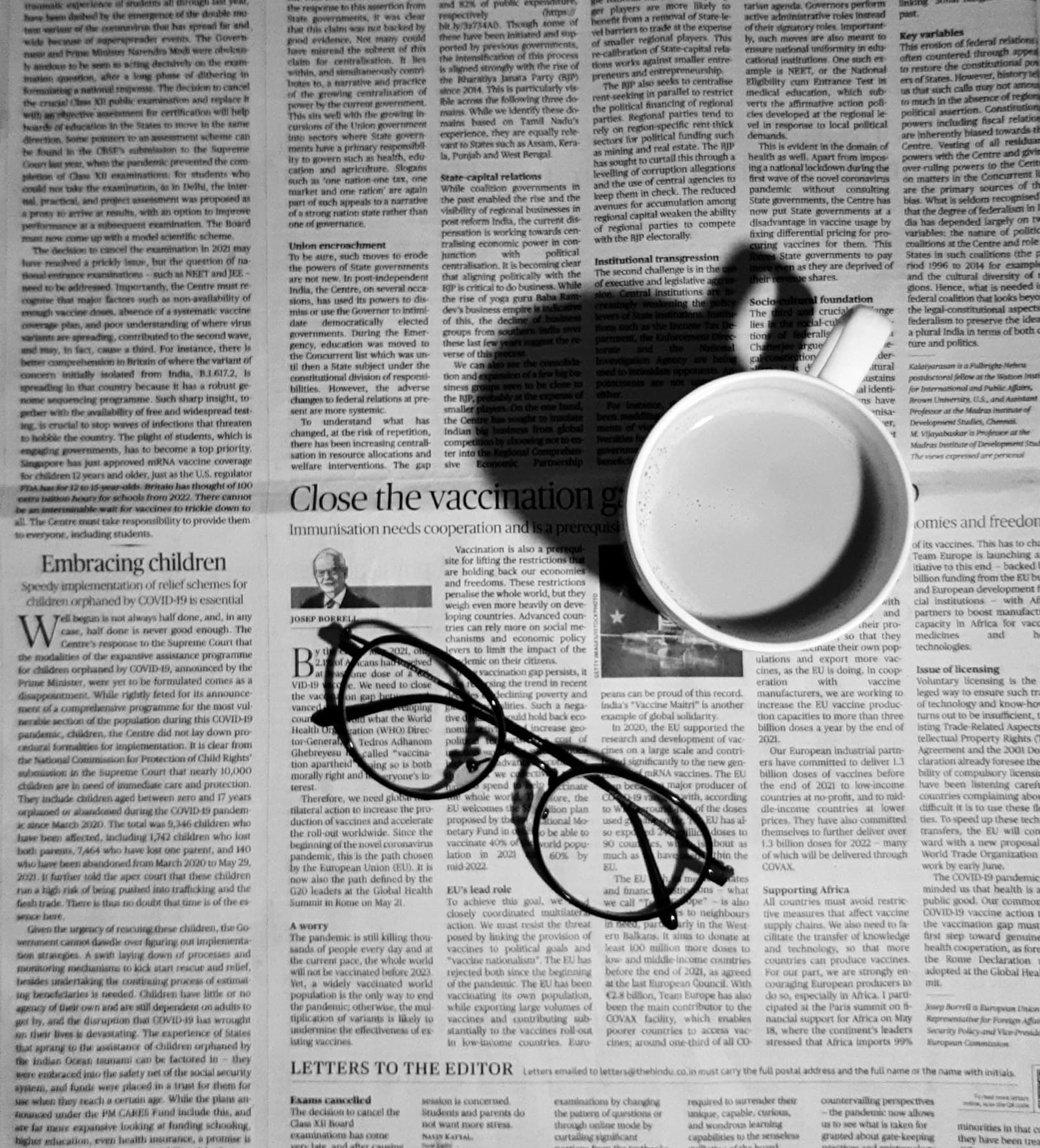 A folded newspaper beside a coffee on a marble surface, morning light.