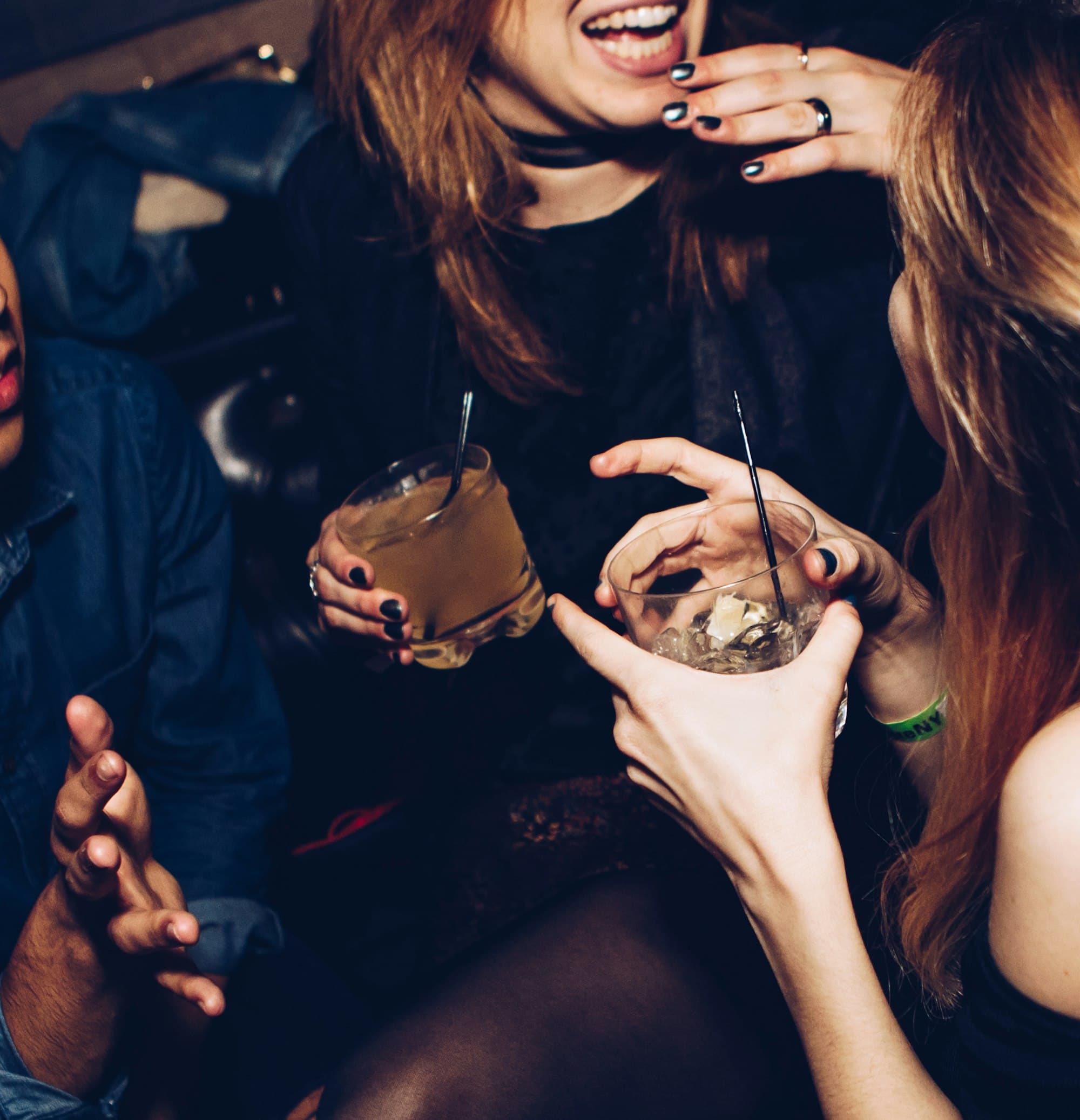 Group of friends laughing around a low table in a private lounge, evening light.