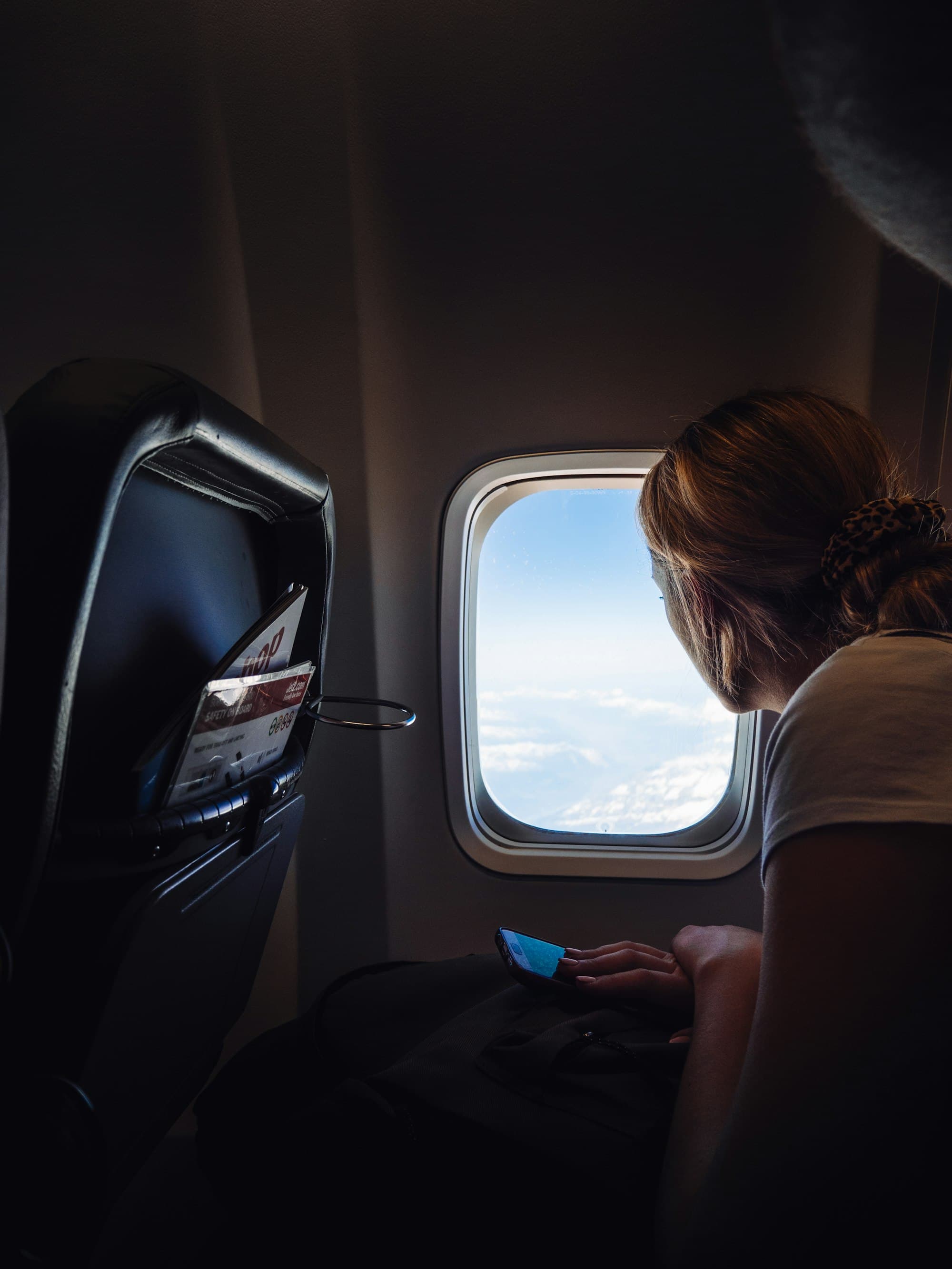 A single passenger reading at the cabin window, soft daylight, no one in the seats around them.