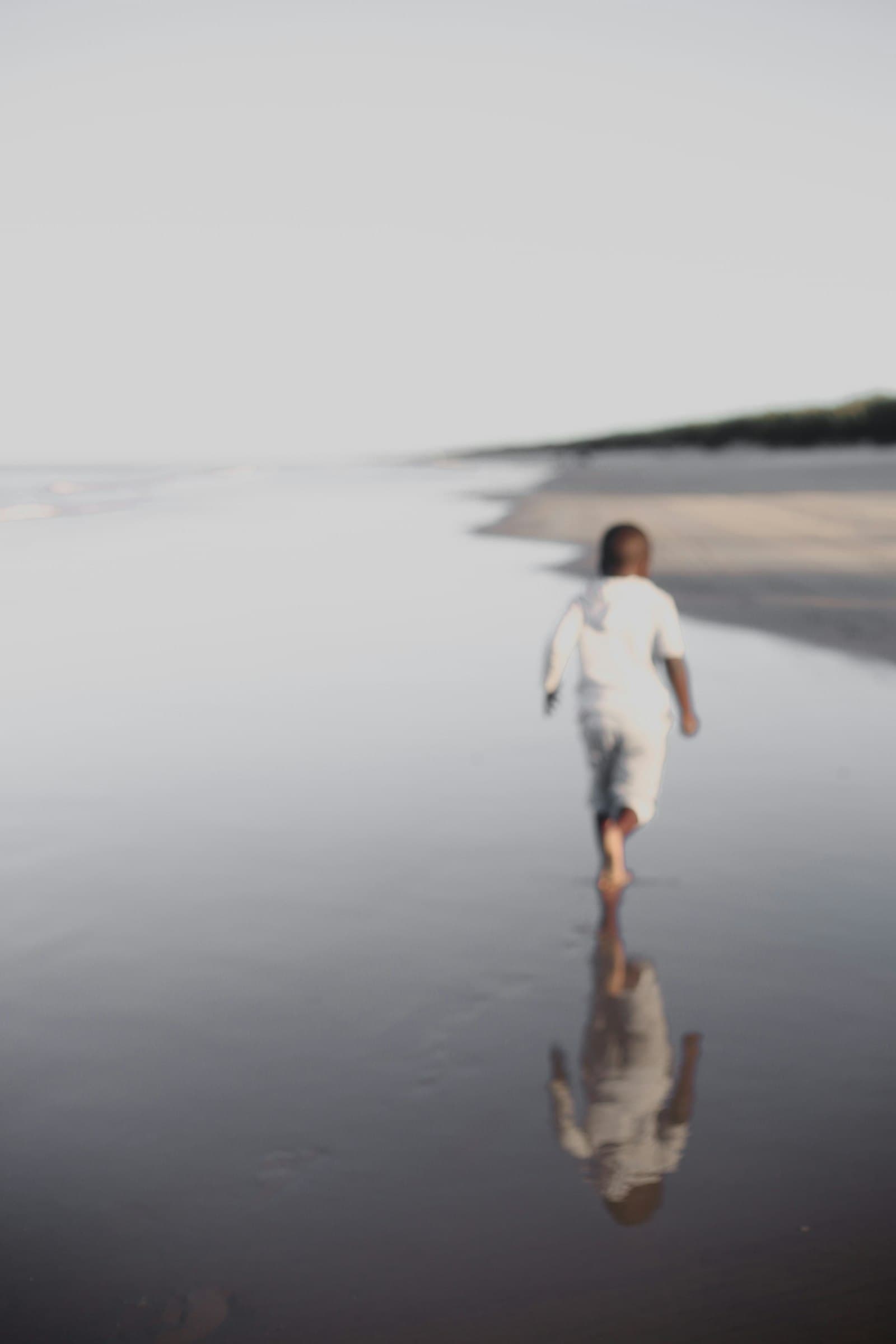 Children running on a wooden walkway through dunes.