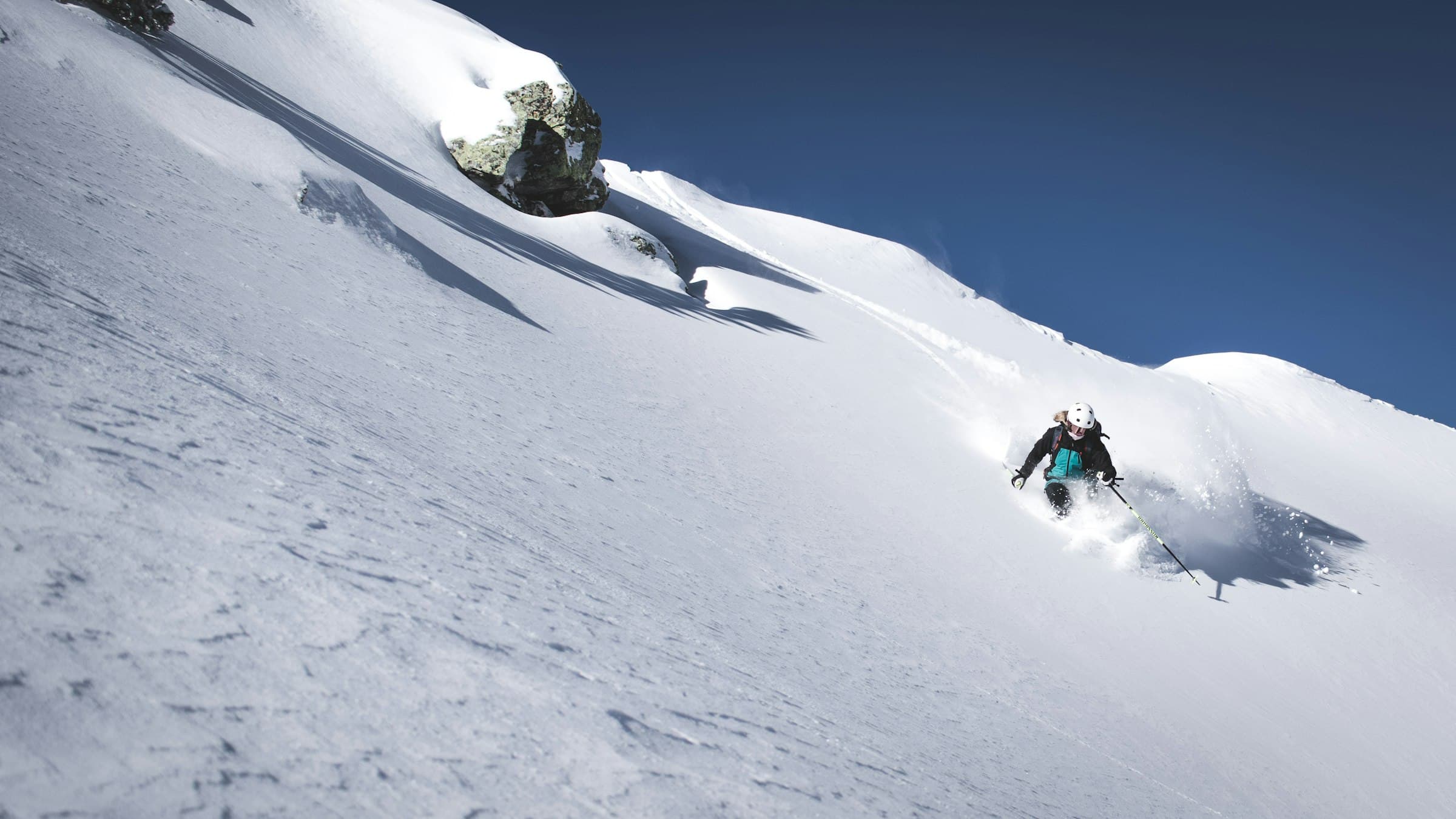 A lone skier dropping into untracked powder beneath Mont Fort, the Bec des Rosses rising in the distance above Verbier.
